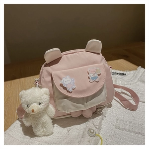 Detail of pink and white rabbit-ear shoulder bag with a plush bear charm and cute patches