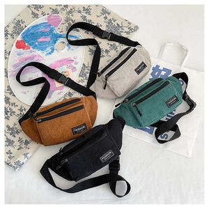 Flat lay of corduroy waist bags in four colors with adjustable nylon straps and labels