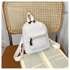 Detail view of a white fuzzy faux fur mini backpack on a vintage chair with an open book