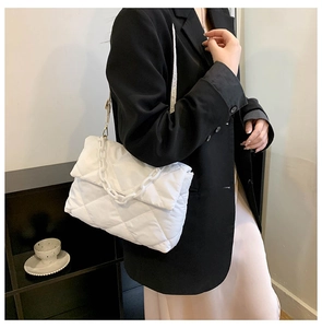 Side view of a white quilted crossbody bag with a thick chain and flap closure