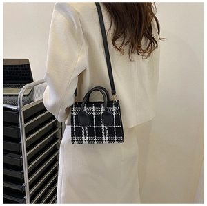 Klassische schwarz-weiße Tweed-Mini-Handtasche als Umhängetasche an einem Model
