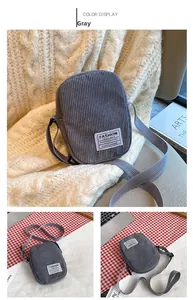 Close-up of a gray corduroy crossbody phone bag with a fashion label and adjustable strap