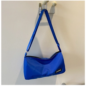 Vue détaillée d'un sac bandoulière en nylon bleu vif avec étiquette mode et fermeture