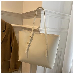 Detail of cream white tote bag with adjustable metal buckle on shoulder strap over wool coat