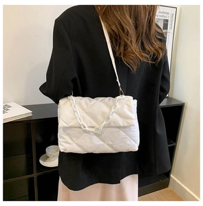 Rear view of a white quilted crossbody bag with chunky chain on a female model