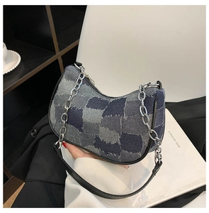 Detail of blue denim patchwork crescent bag with silver chain and leather shoulder strap