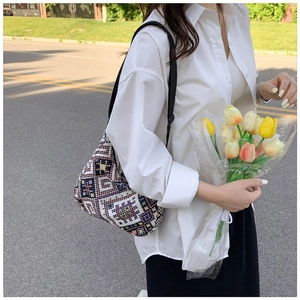Détail d'un sac sous les bras en tricot ethnique aux motifs géométriques violets et jaunes