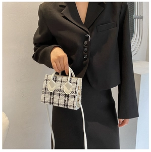 Detailansicht der schwarz-weißen Tweed-Minitsche mit weißem Ledergriff und Schultergurt
