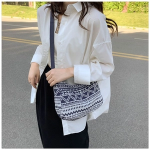 Detail of bohemian knit crossbody bag featuring blue and white geometric wave patterns