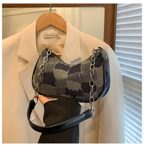 Detail of patchwork denim shoulder bag with silver chain and leather strap on beige blazer