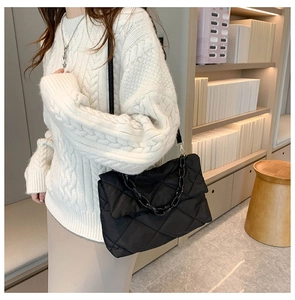 Detailed view of black quilted chain bag with thick resin strap shown on model