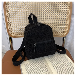 Detailed view of black fuzzy shearling mini backpack on a vintage wooden chair