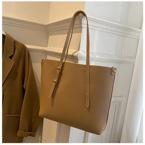 Detail of light brown leather tote bag with adjustable strap and golden metal buckle
