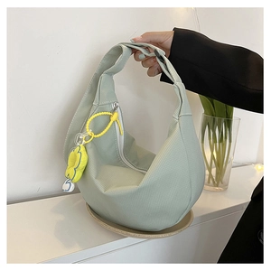 Détail du sac hobo en velours côtelé vert clair avec charme fleur jaune et zip blanc