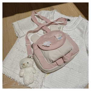 Detail of pink canvas bag with bunny ears, plush bear charm, and cartoon pins
