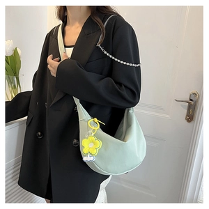 Détail du sac croissant vert clair avec pendentif décoratif de tournesol jaune