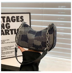 Detail of blue denim patchwork bag with silver metal chain and raw edge texture