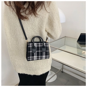 Detailansicht der schwarz-weiß karierten Tweed-Handtasche mit Lederriemen im Alltag