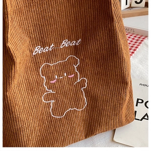 Dettaglio della borsa tote in velluto a coste caramello con ricamo a forma di orso