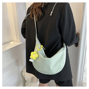 Vue détaillée du sac demi-lune vert clair avec charm fleur jaune sur mannequin
