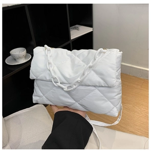 Close-up of white quilted puffer shoulder bag with a thick decorative chain strap
