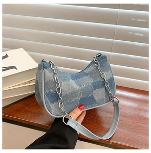 Detailed close-up of blue denim patchwork hobo bag with silver chain and leather strap