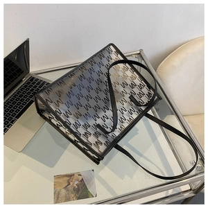 Close-up of transparent PVC tote bag with geometric M-pattern and black leather trim