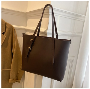Detail of dark brown leather tote bag with gold metal buckles and hanging shoulder straps