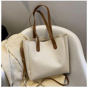 Detail of soft cream leather tote with brown handles on a white chair background