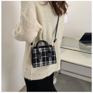 Détail du sac bandoulière en tweed à carreaux avec poignées noires et ferrures dorées