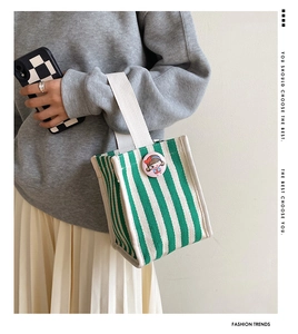 Detail of green and white striped canvas tote bag with decorative cartoon brooch