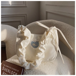 Detail der weißen Plissee-Handtasche mit blauer Herz-Wal-Stickerei auf Fleece-Sessel