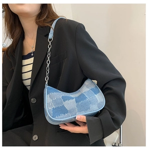 Close-up of a blue patchwork denim shoulder bag with a silver chain and leather strap