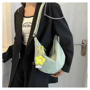 Détail du sac bandoulière croissant vert clair avec pendentif tournesol sur le mannequin
