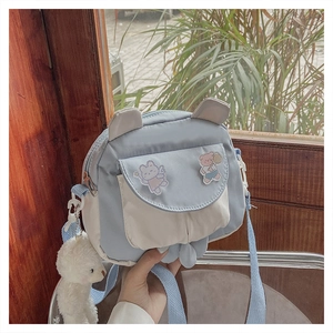 Detail of cute blue and cream crossbody bag with plush bear charm and animal ear accents