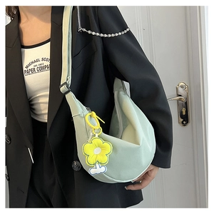 Détail du sac croissant en velours côtelé vert clair avec bandoulière et breloque fleur