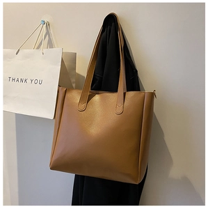 Detail view of brown leather tote bag with reinforced V-stitching and smooth texture