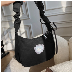 Detail der schwarzen Plissee-Tasche mit blauem Herz-Patch und Wal-Stickerei-Dekoration