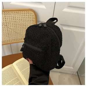 Close-up of black fuzzy lamb wool mini backpack featuring zippered front pocket and straps