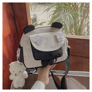Detail of panda-style canvas crossbody bag with cute stickers and plush bear charm