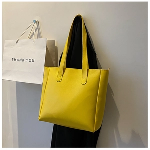 Close-up of a yellow tote bag with pebble leather texture hanging on a wall hook