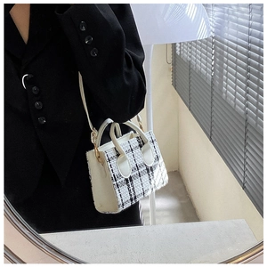 Detail einer schwarz-weißen Tweed-Mini-Tasche mit Lederbesatz und goldenen Beschlägen