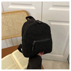 Close-up of black fleece mini backpack with fuzzy texture and metal zipper detail