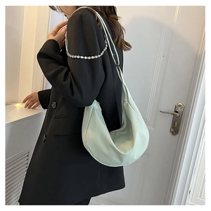 Sac à bandoulière demi-lune vert clair porté par un mannequin sur fond blanc épuré