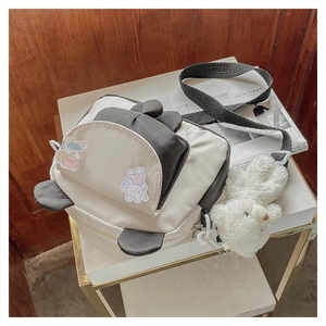 Detail of canvas crossbody bag with cartoon bunny print and plush bear keychain accessory
