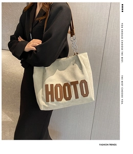 Détail du grand sac cabas en toile avec écusson HOOTO et bandoulière chaîne sur modèle