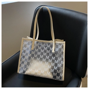 Detail of transparent PVC tote bag with white M-letter pattern and cream leather trim