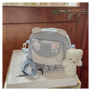 Close-up of light blue cartoon bunny crossbody bag with plush bear charm and 3D ears