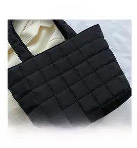 Detail shot of black quilted tote bag showing puffy square texture and padded handle