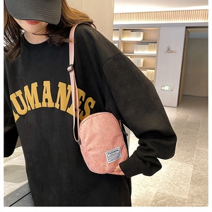 Close-up of pink corduroy mini crossbody bag with adjustable strap worn by a model